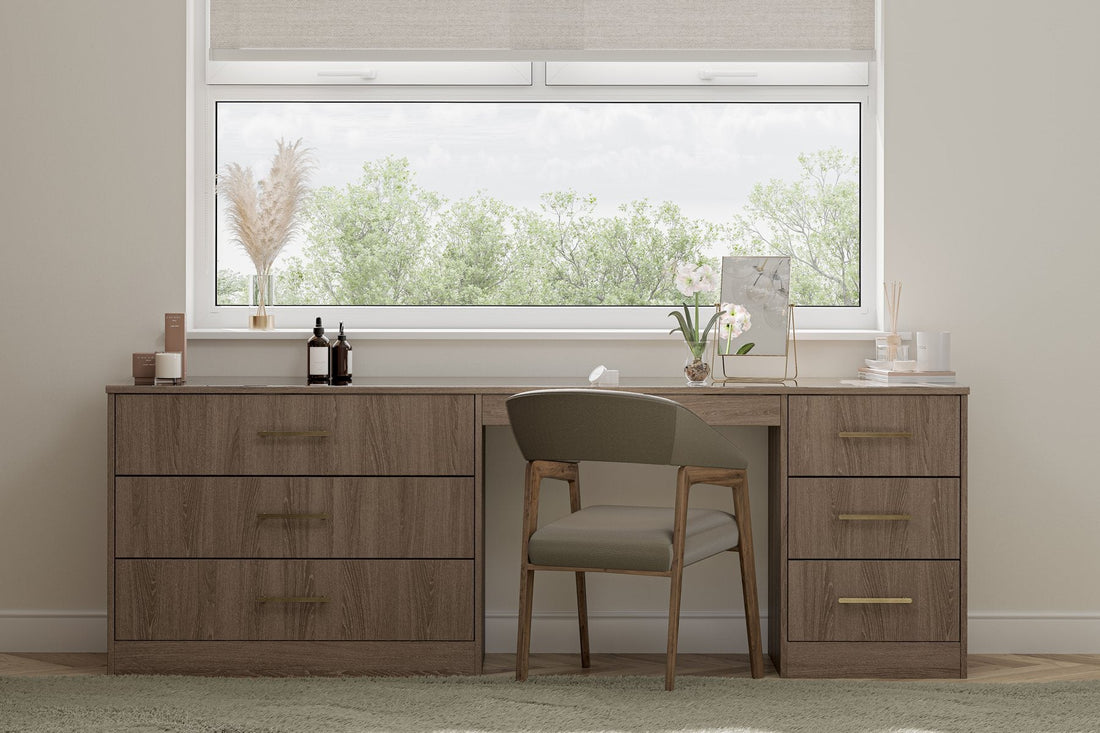Dark oak fitted drawers and dressing table beneath a window