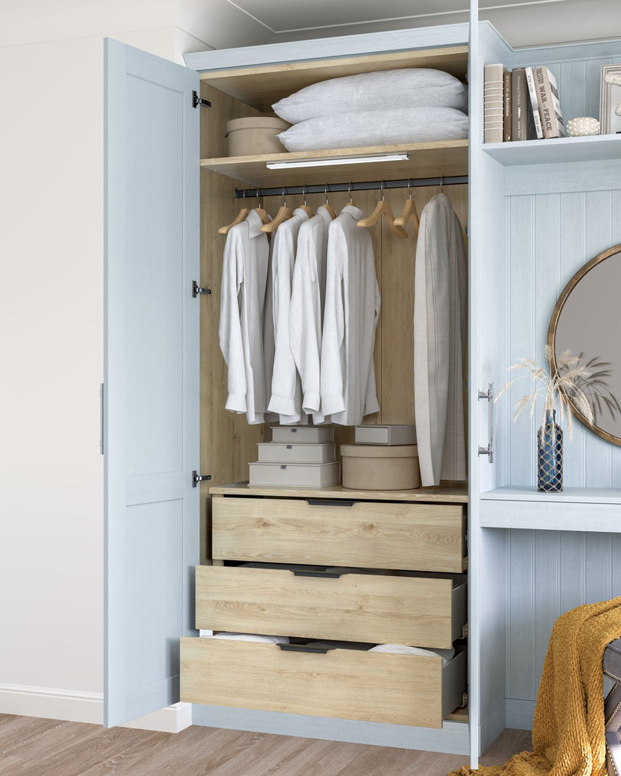 Pale blue wardrobe open to show hanging and an oak drawer