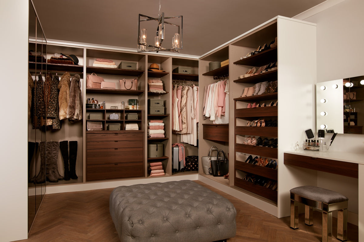 Walk-in dressing room in white and walnut with a central ottoman and lit shoe shelves