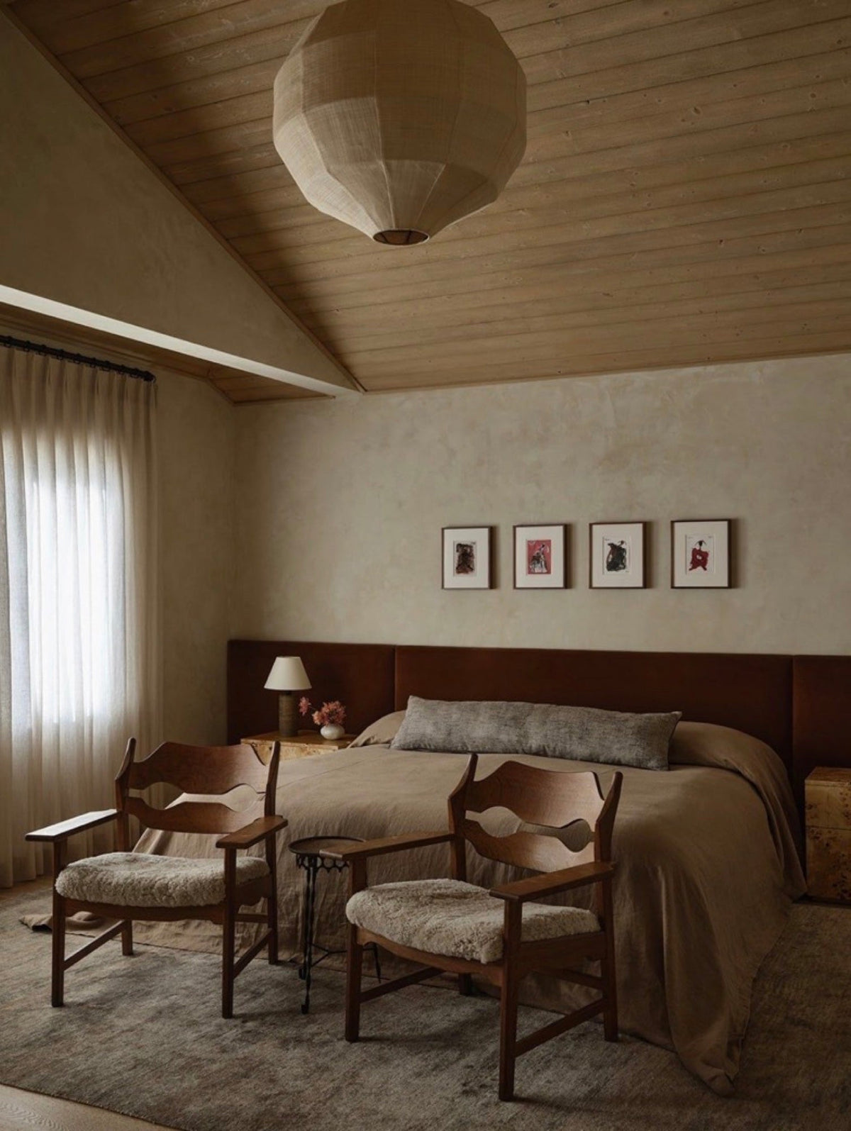 Wall-width upholstered headboard in a plastered bedroom with two armchairs