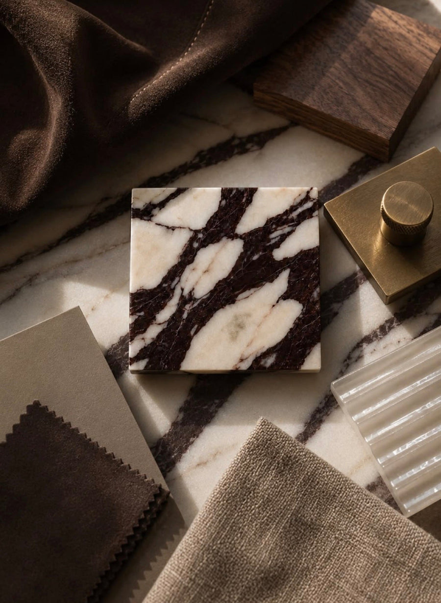 Material samples: marble, walnut, brass and suede laid out in daylight