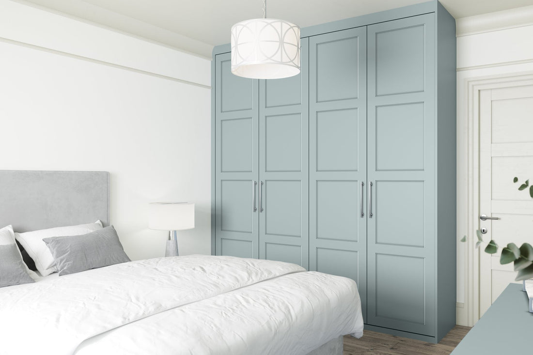 Matt blue made-to-measure Shaker wardrobes beside a bed