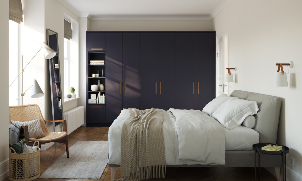 Charcoal handleless slab wardrobes with brass edge grips behind a bed